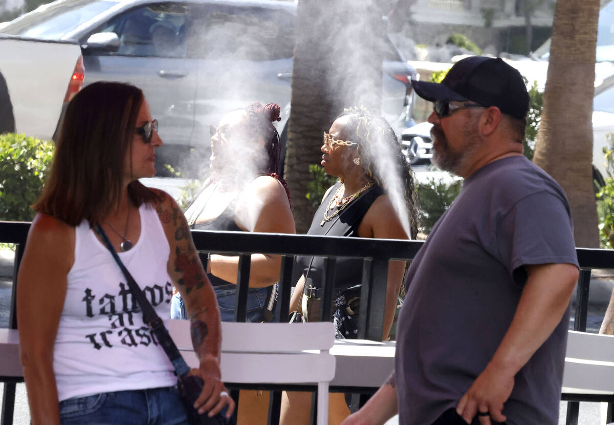 Pedestrians cool off with water misters along the Las Vegas Strip during a hot Thursday afterno ...